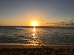 crossing the bar sunset symbolism—golden sun sets over tranquil ocean, faint sandbar visible, symbolizing transition.