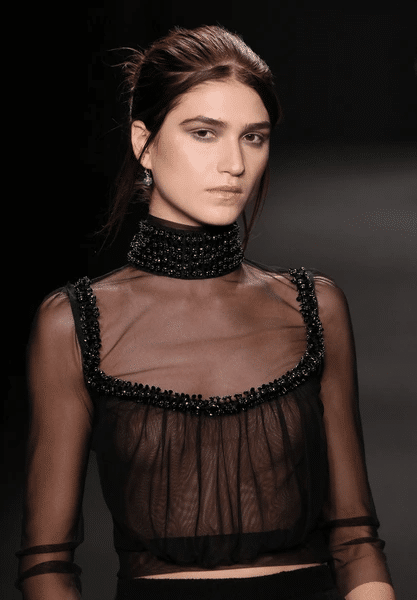 Model wearing a sheer black dress on runway
