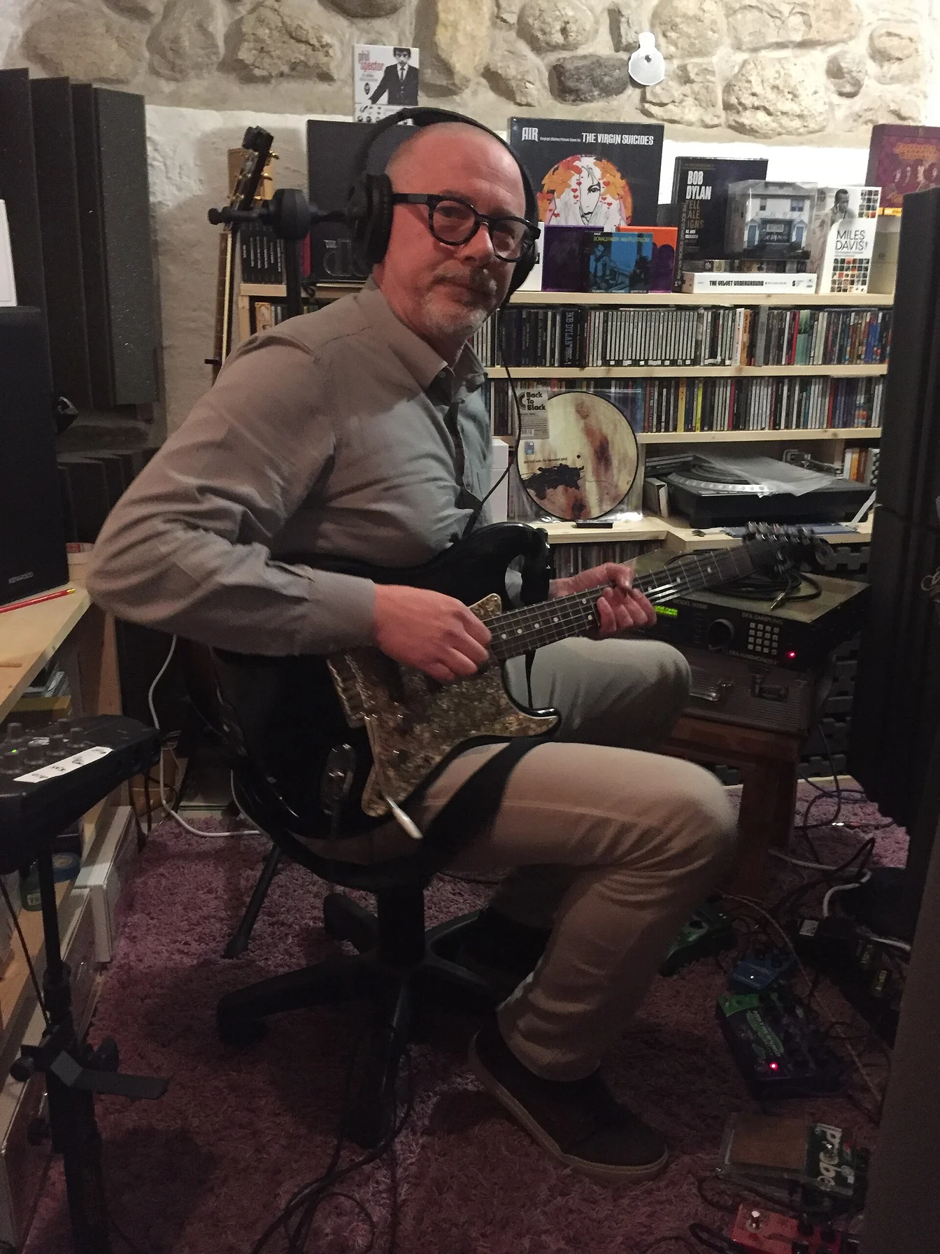 Miley Cyrus in a recording studio with headphones, surrounded by guitars and equipment