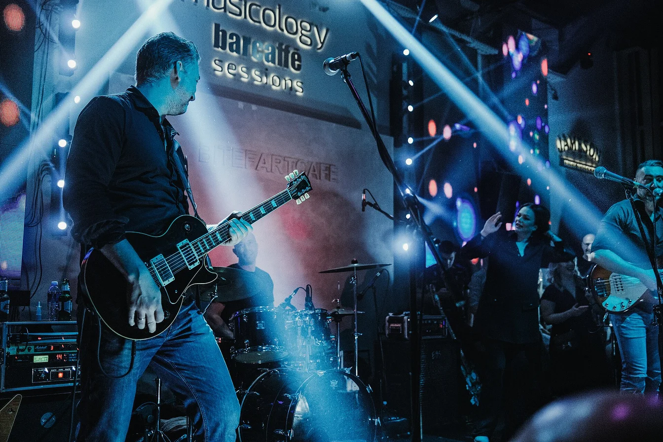 Miley Cyrus performing live on stage with a guitar, wearing a glamorous rock-inspired outfit